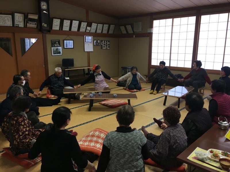参加者が輪になって手をつなぎ歌っている様子