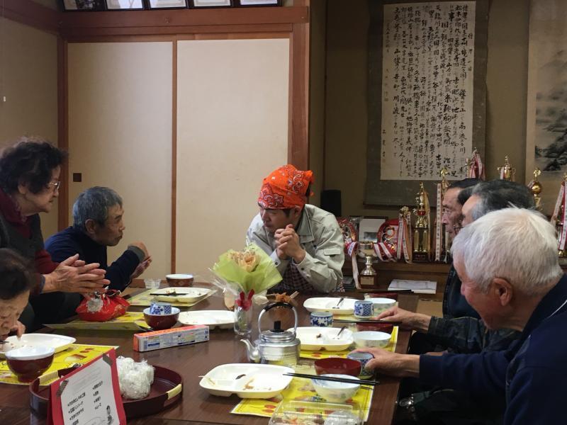 テーブルの上に置かれたカラマツの花を囲んで話す参加者とスタッフ