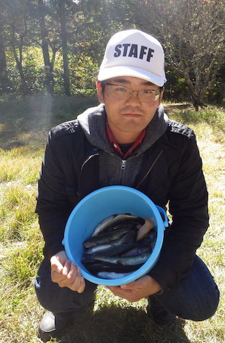 バケツの中の釣れた魚を見せる男性