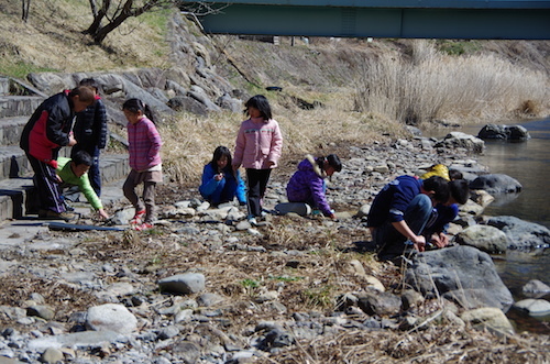 博物館脇の河原で石拾いをする子供たちの様子